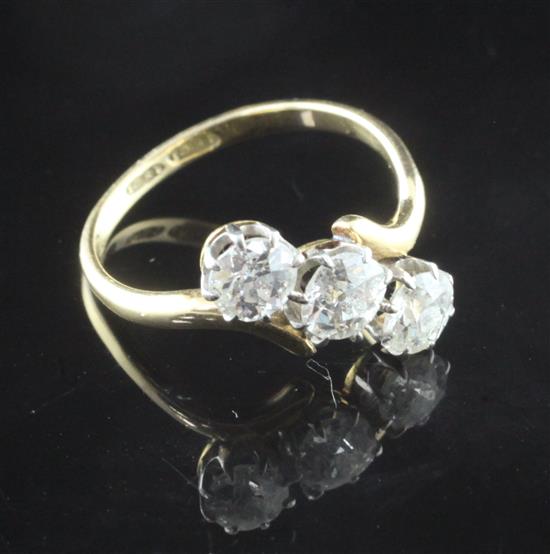An 18ct gold and three stone diamond cross-over ring, size N.